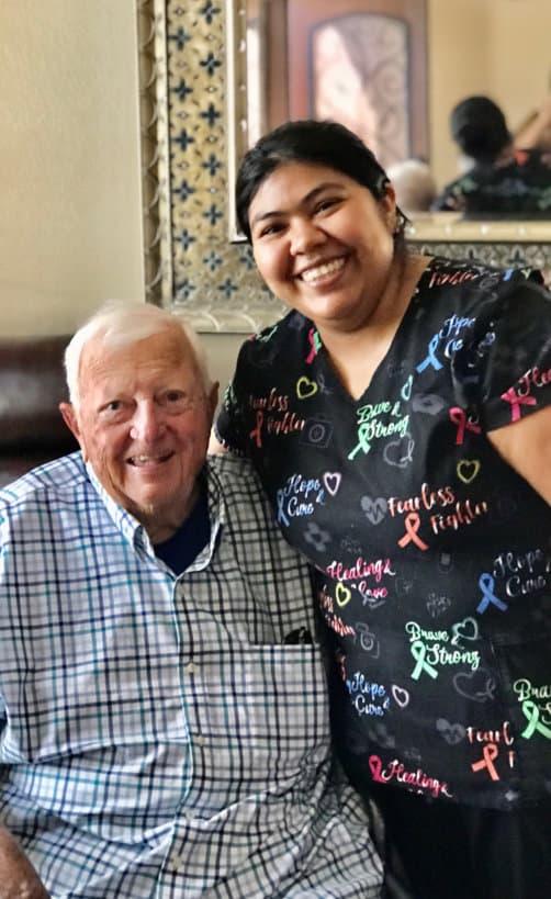 caregiver and an elderly man smiling at the camera