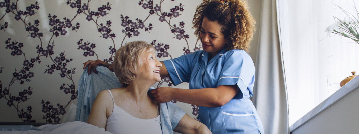 caregiver helping an elderly woman get clothes